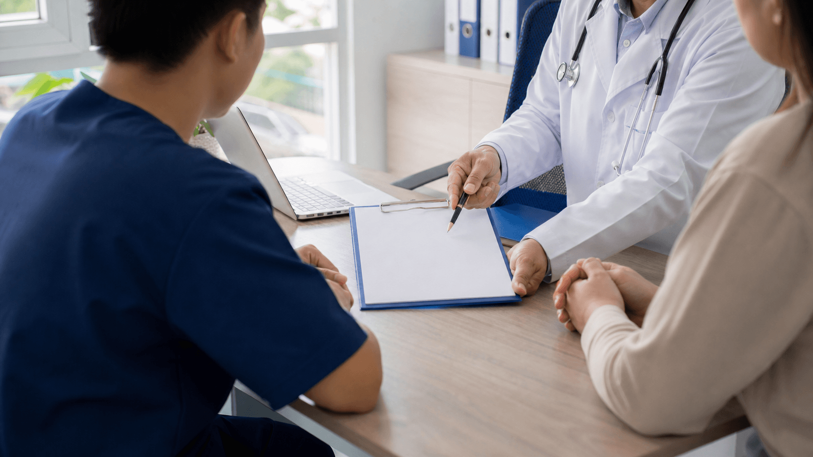 Supervised medical student observing a clinician explain a blank consent form in a Vietnamese teaching room